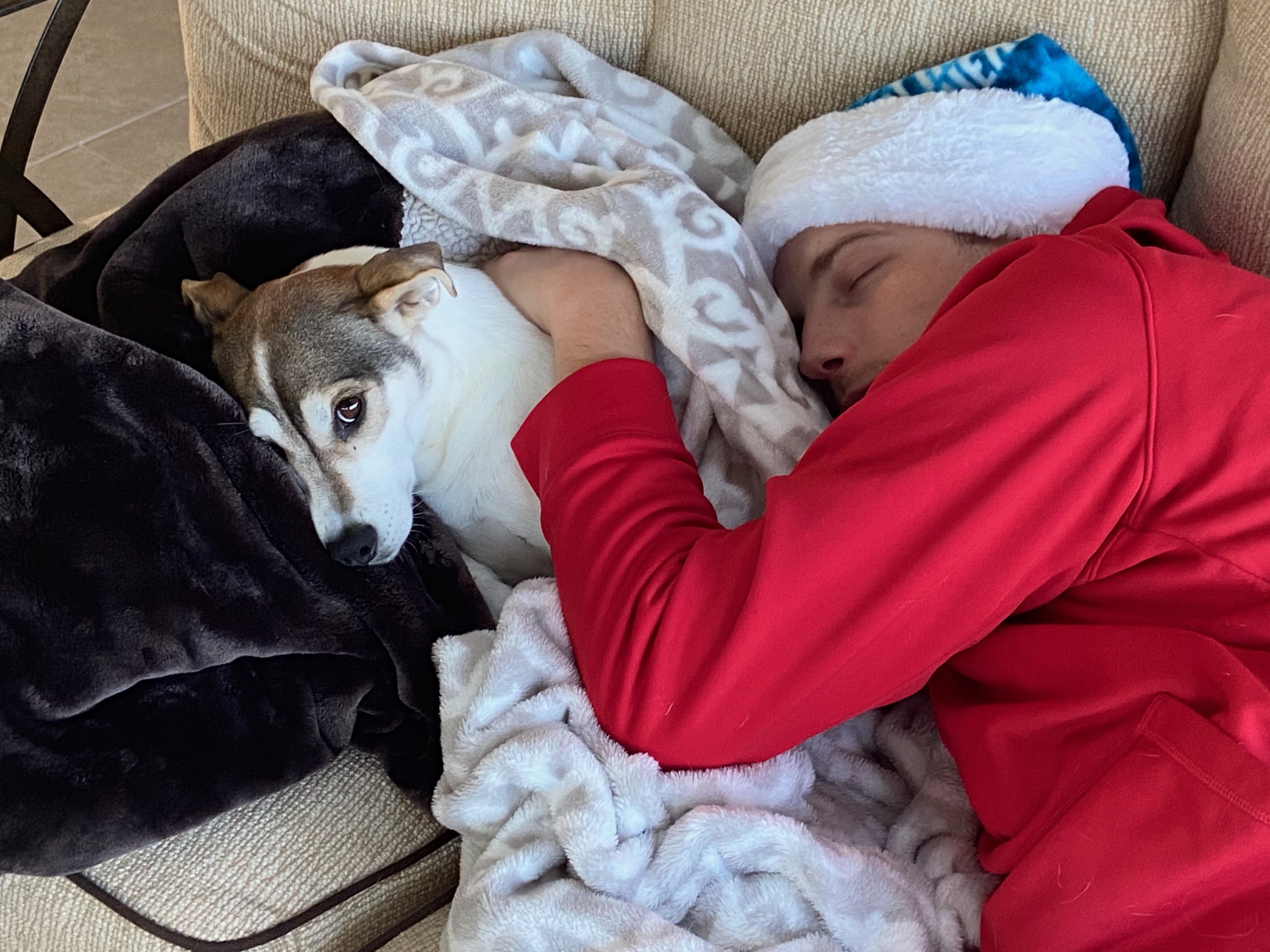 image of man sleeping on his side with his arm draped around his dog